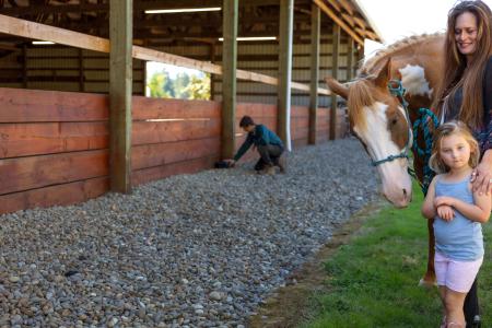 Mom and daughter with horse while man applies pest control products